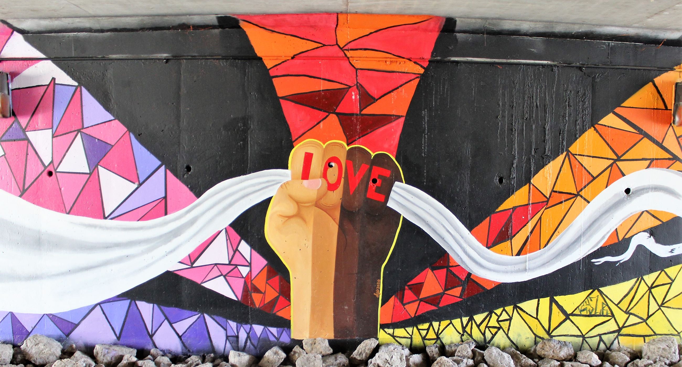 A fist with the word Love is part of the Unity mural in the Lincoln Highway underpass