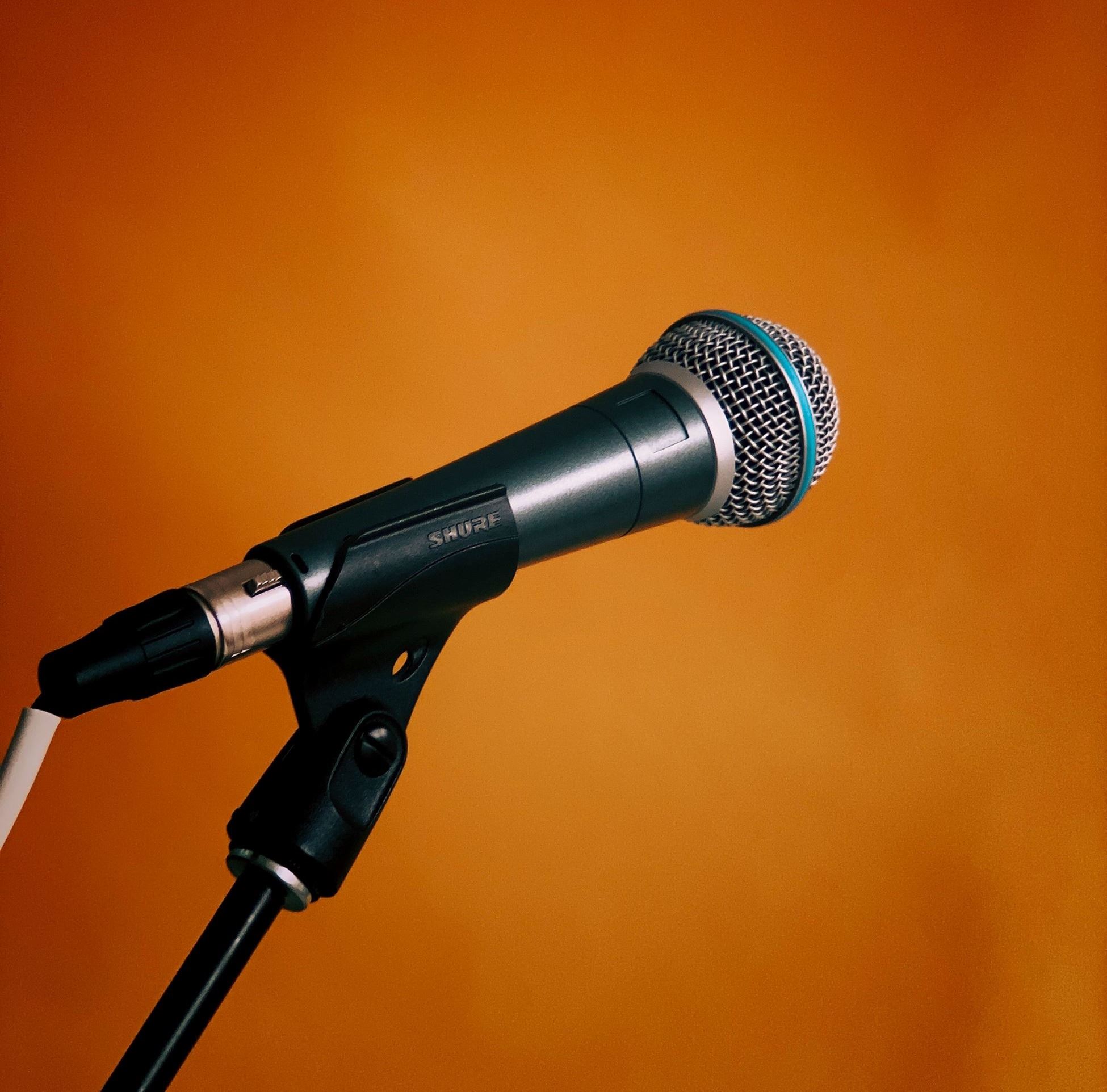 A microphone in front of an orange background