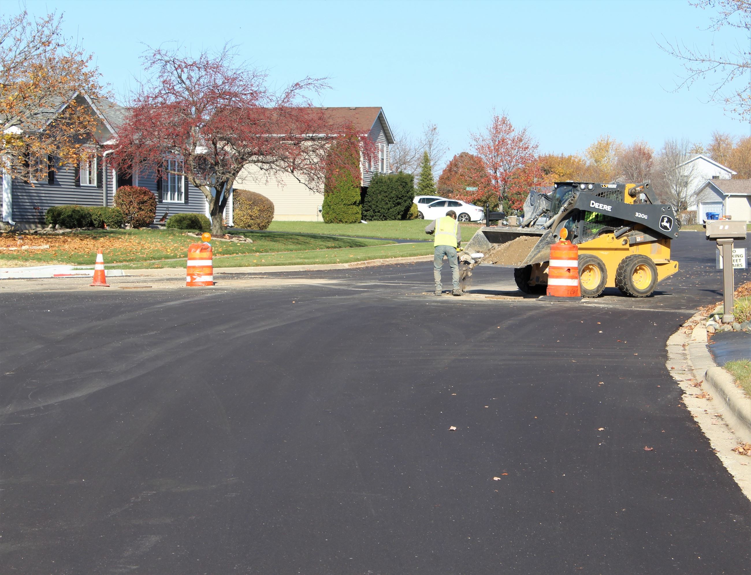 Work is done around a manhole cover following road resurfacing in the Knolls in fall 2022.